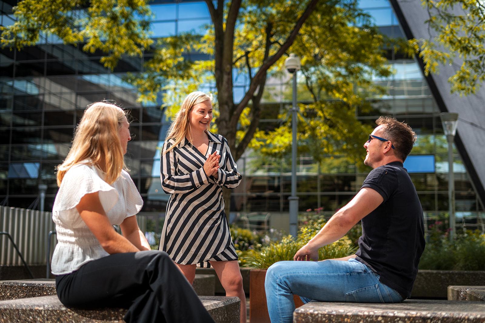 Drie collega's in gesprek in de grote, groene binnentuin van YourMeeting.